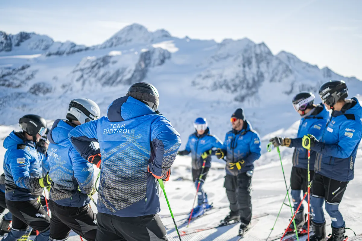 Trainer bespricht sich mit dem Rennteam in blauen Energiapura-Jacken