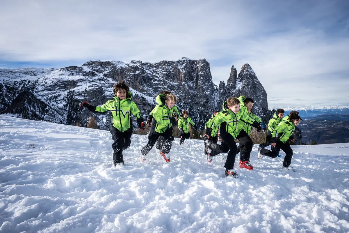 Nachwuchsläufer in individuell gestalteten grünen Energiapura-Clubjacken laufen durch den Schnee