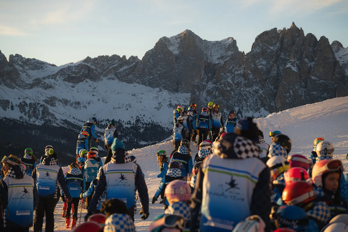Nachwuchsgruppe eines Skiclubs in blau-weißen Clubjacken vor den Dolomiten